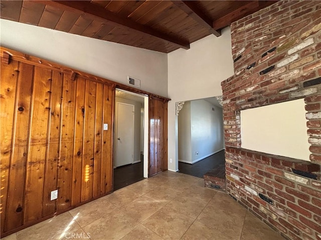 empty room with wood ceiling, beam ceiling, high vaulted ceiling, and brick wall