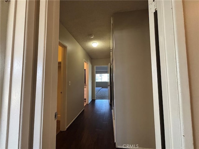 corridor with dark wood-type flooring and a textured ceiling