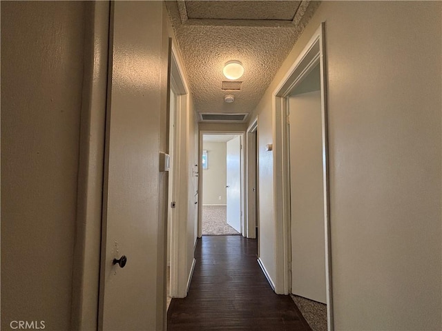 hallway featuring dark wood-type flooring and a textured ceiling