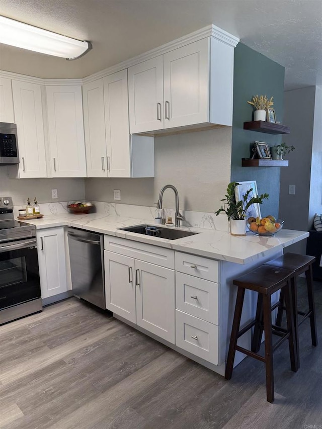 kitchen with sink, stainless steel appliances, light hardwood / wood-style floors, and white cabinets