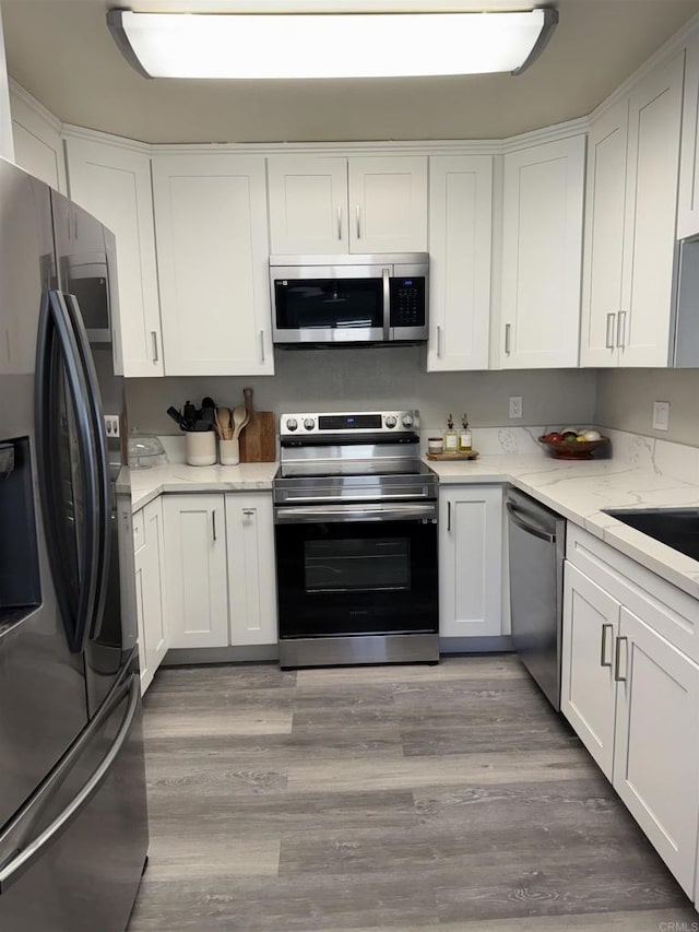 kitchen featuring stainless steel appliances, white cabinetry, sink, and light wood-type flooring