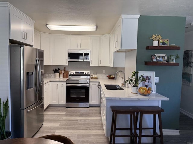 kitchen with white cabinetry, stainless steel appliances, sink, and a breakfast bar area