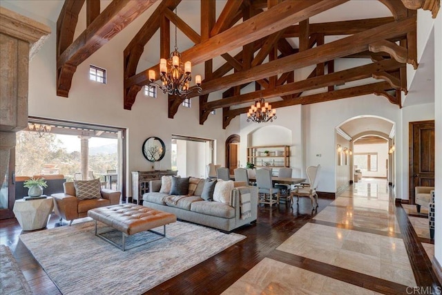 living room with an inviting chandelier, beam ceiling, and a high ceiling