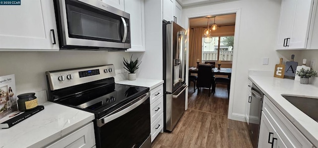 kitchen with stainless steel appliances, white cabinetry, dark wood-type flooring, and pendant lighting