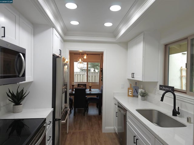 kitchen with sink, appliances with stainless steel finishes, white cabinetry, light stone counters, and ornamental molding