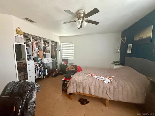 tiled bedroom with ceiling fan and a closet