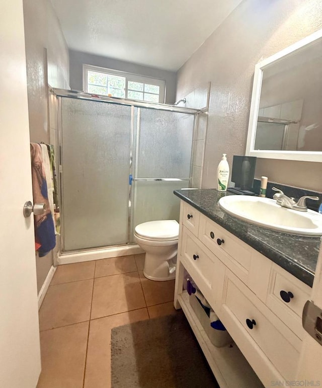 bathroom with tile patterned flooring, vanity, walk in shower, and toilet