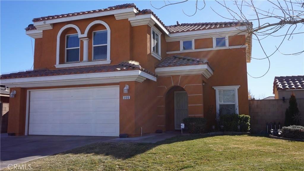 mediterranean / spanish-style house featuring a garage and a front yard