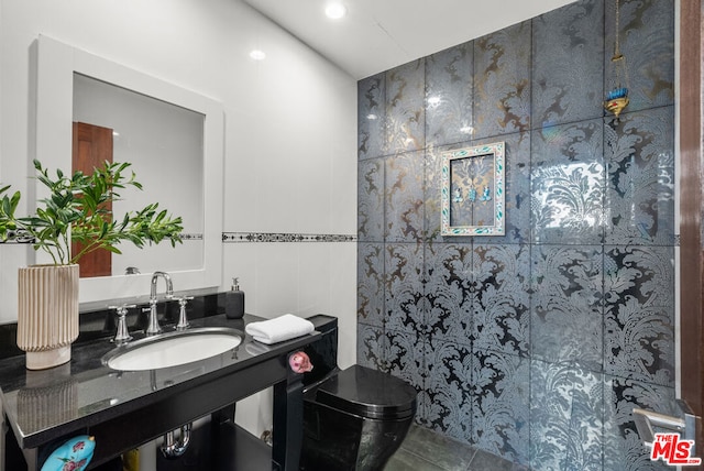 bathroom featuring tile patterned flooring, sink, and tile walls