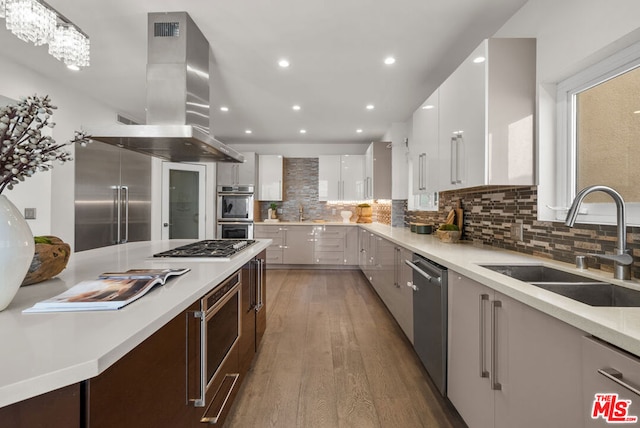 kitchen featuring appliances with stainless steel finishes, island range hood, white cabinetry, sink, and dark hardwood / wood-style flooring