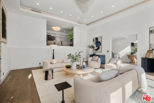 living room with hardwood / wood-style flooring, an inviting chandelier, and a tray ceiling