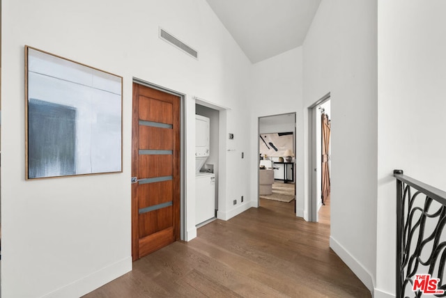 corridor with stacked washer and clothes dryer and dark hardwood / wood-style flooring