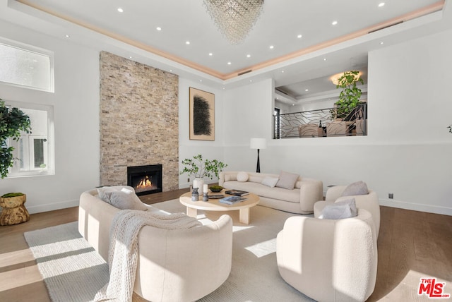 living room with a fireplace, a tray ceiling, and light hardwood / wood-style flooring