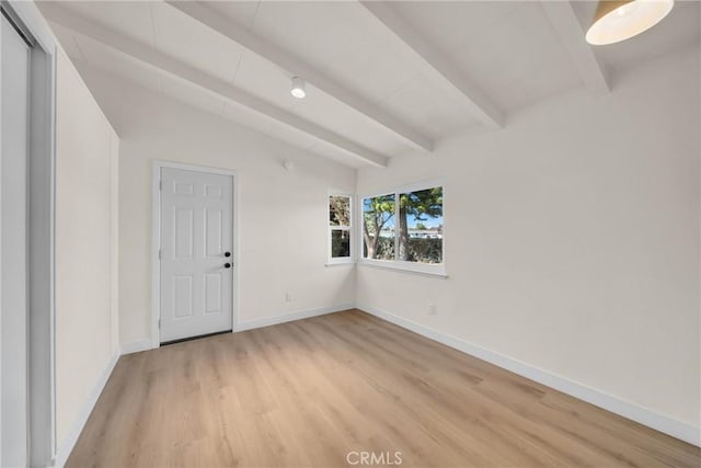 empty room featuring vaulted ceiling with beams and light hardwood / wood-style floors