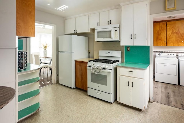 kitchen featuring white cabinetry, white appliances, and independent washer and dryer