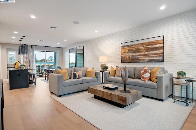 living room featuring brick wall and light hardwood / wood-style floors