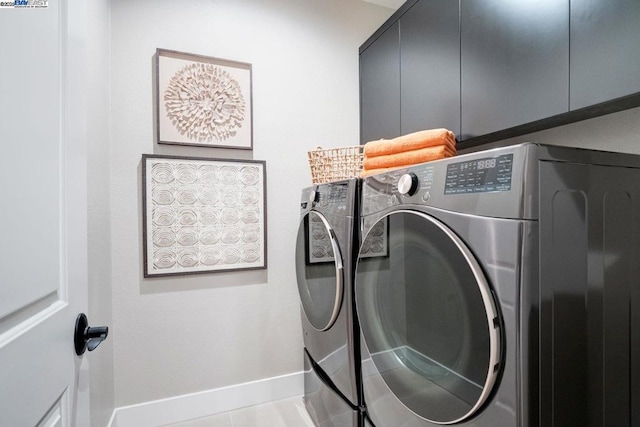 laundry room featuring tile patterned flooring, cabinets, and washing machine and clothes dryer