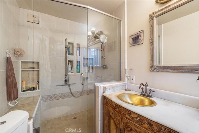 bathroom featuring a shower with door, vanity, and toilet