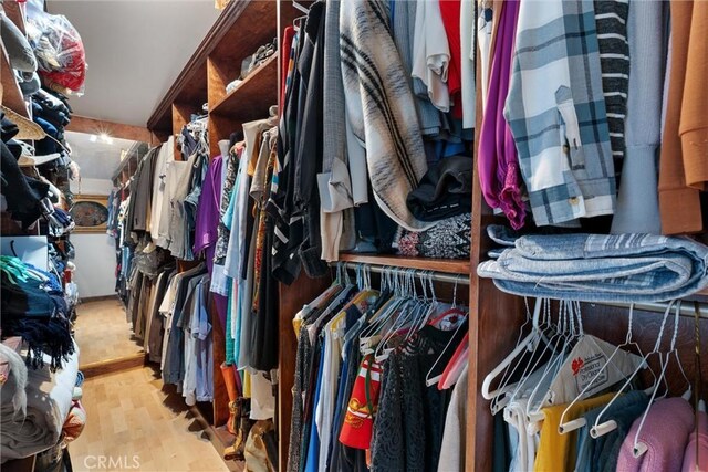 walk in closet with light hardwood / wood-style floors