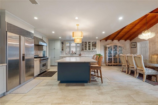 kitchen with a kitchen island, lofted ceiling with beams, decorative light fixtures, wall chimney range hood, and premium appliances