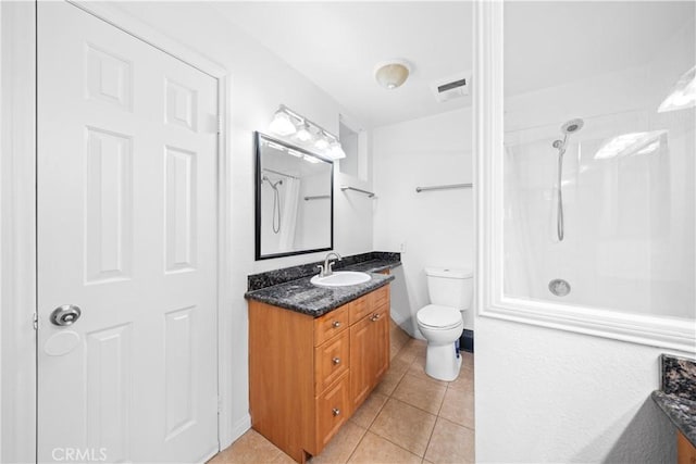 bathroom featuring toilet, vanity, tile patterned floors, and walk in shower