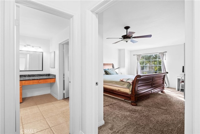 tiled bedroom with ceiling fan, connected bathroom, and built in desk