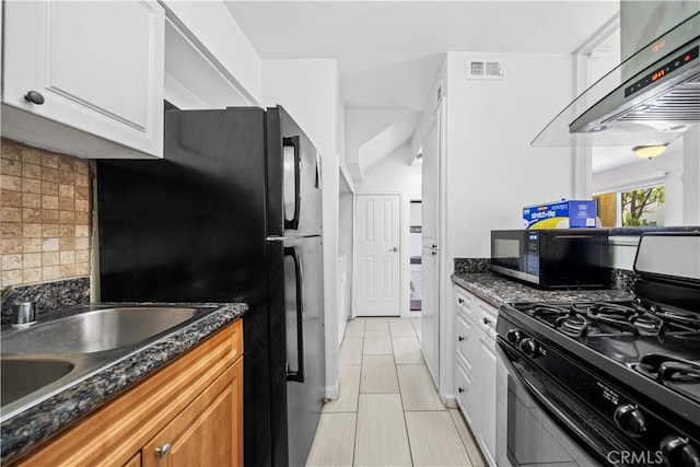 kitchen featuring black refrigerator, range with gas stovetop, white cabinets, decorative backsplash, and exhaust hood