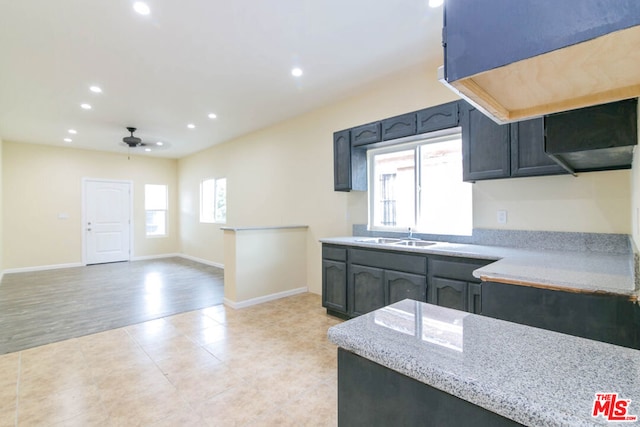 kitchen with light stone countertops, sink, ceiling fan, and light hardwood / wood-style flooring