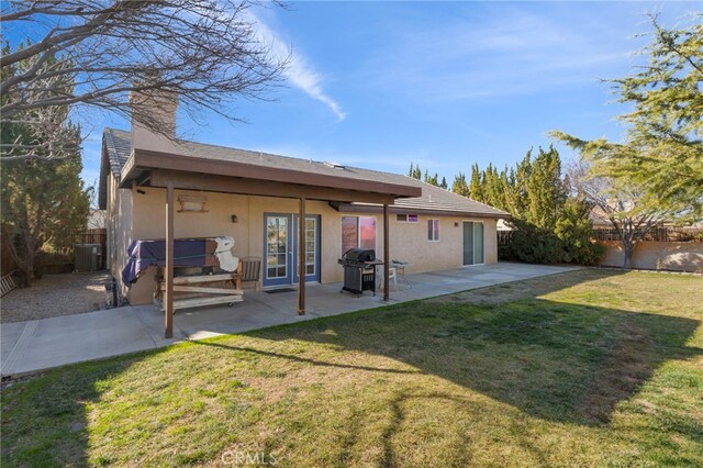 back of property with central AC, a patio, and a lawn