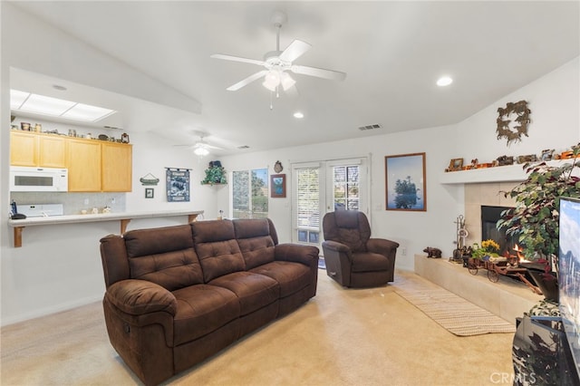 living room featuring ceiling fan, light carpet, and a fireplace