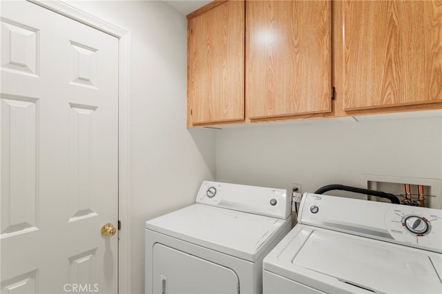 clothes washing area featuring cabinets and washer and dryer