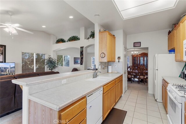 kitchen with light tile patterned flooring, sink, tile countertops, kitchen peninsula, and white appliances