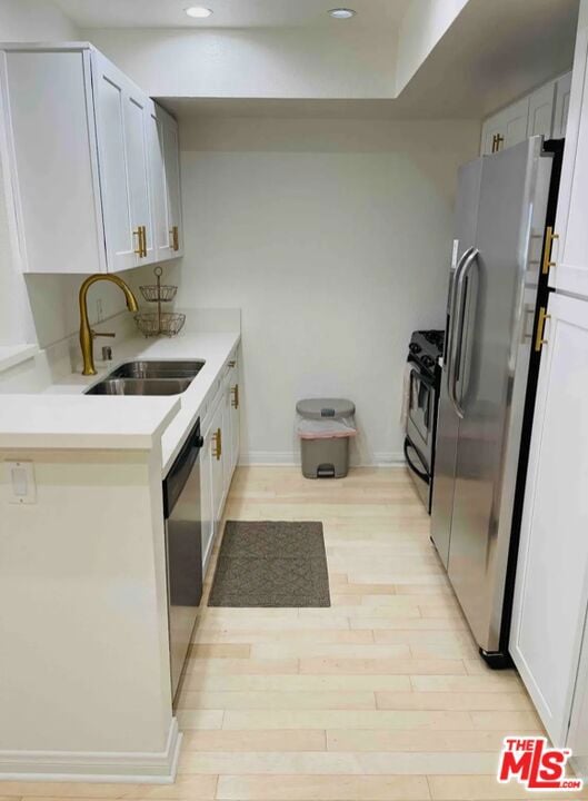 kitchen featuring white cabinetry, appliances with stainless steel finishes, sink, and light wood-type flooring