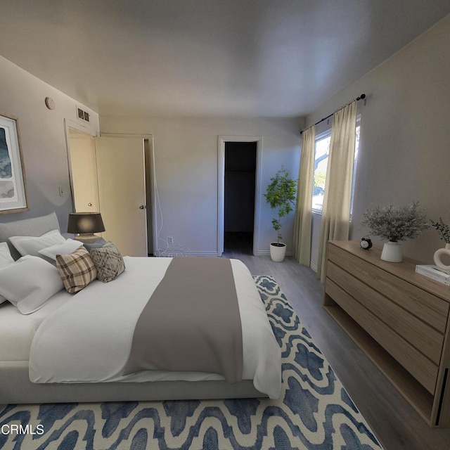 bedroom with a walk in closet and wood-type flooring