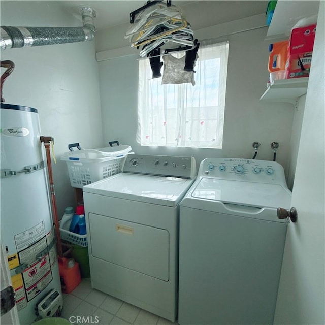 washroom with strapped water heater, light tile patterned floors, and washing machine and dryer