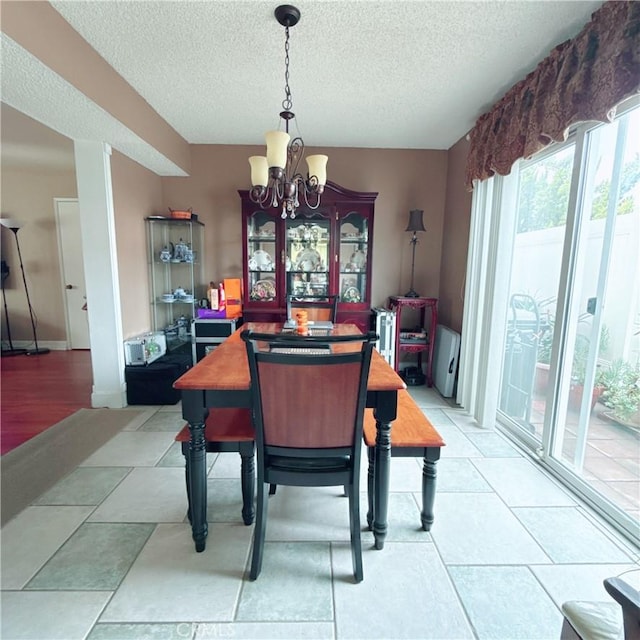 dining room with light tile patterned flooring, a textured ceiling, and a notable chandelier