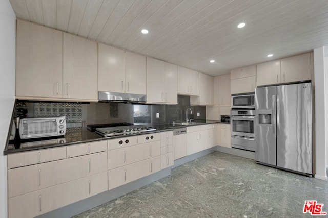 kitchen featuring tasteful backsplash, sink, cream cabinetry, and appliances with stainless steel finishes