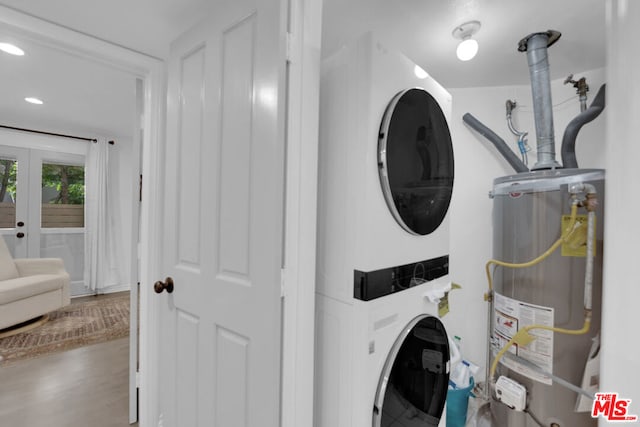 washroom featuring french doors, stacked washer and clothes dryer, wood-type flooring, and water heater