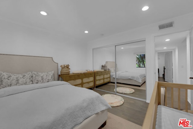 bedroom with hardwood / wood-style flooring, ornamental molding, and a closet