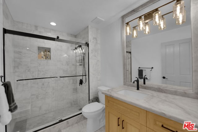 bathroom featuring a shower with door, vanity, and toilet