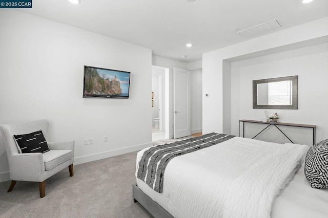 bedroom with ensuite bath and light colored carpet