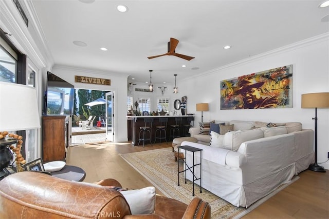 living room with ceiling fan, ornamental molding, and light hardwood / wood-style flooring