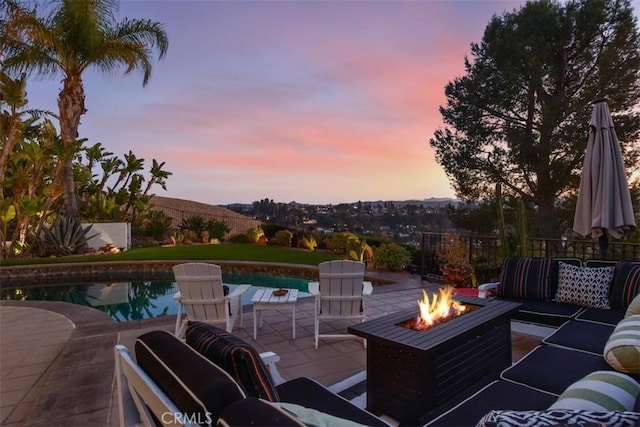 patio terrace at dusk with a fenced in pool and an outdoor living space with a fire pit