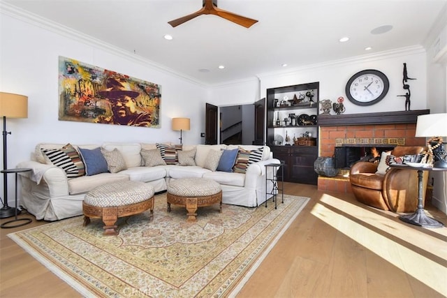 living room featuring crown molding, wood-type flooring, and a brick fireplace