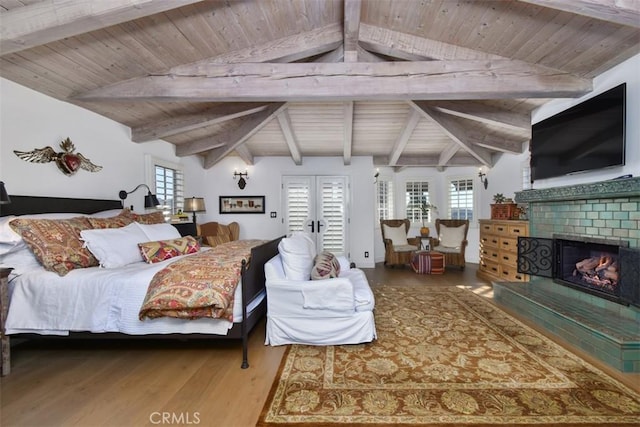 bedroom with wood ceiling, wood-type flooring, lofted ceiling with beams, a brick fireplace, and french doors