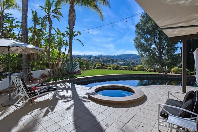 view of patio featuring a swimming pool with hot tub and a mountain view