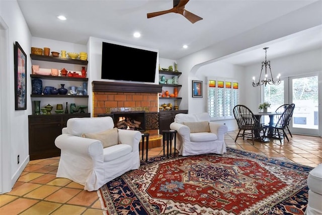 living room with a fireplace, ceiling fan with notable chandelier, and light tile patterned floors