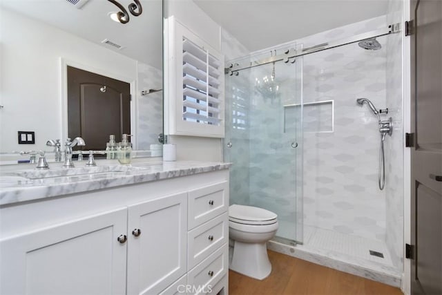 bathroom featuring hardwood / wood-style flooring, vanity, a shower with door, and toilet