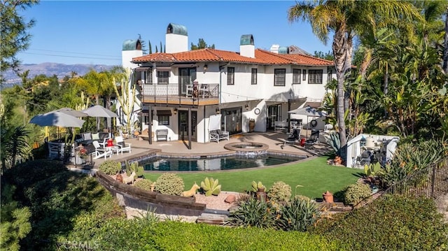 rear view of property featuring a balcony, a patio, a swimming pool with hot tub, and a lawn