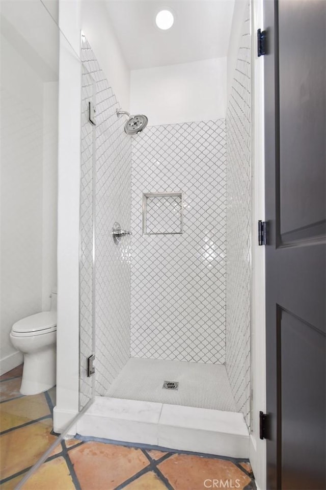 bathroom featuring tiled shower and toilet